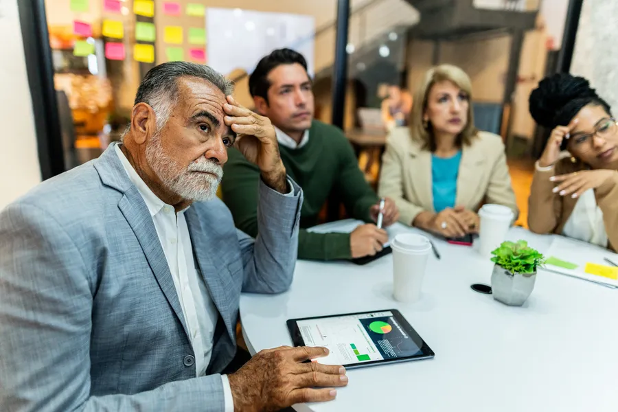 Worried senior businessman listening presentation