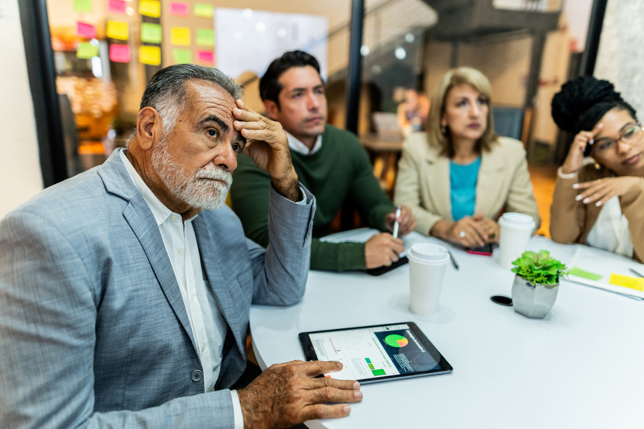 Worried senior businessman listening presentation